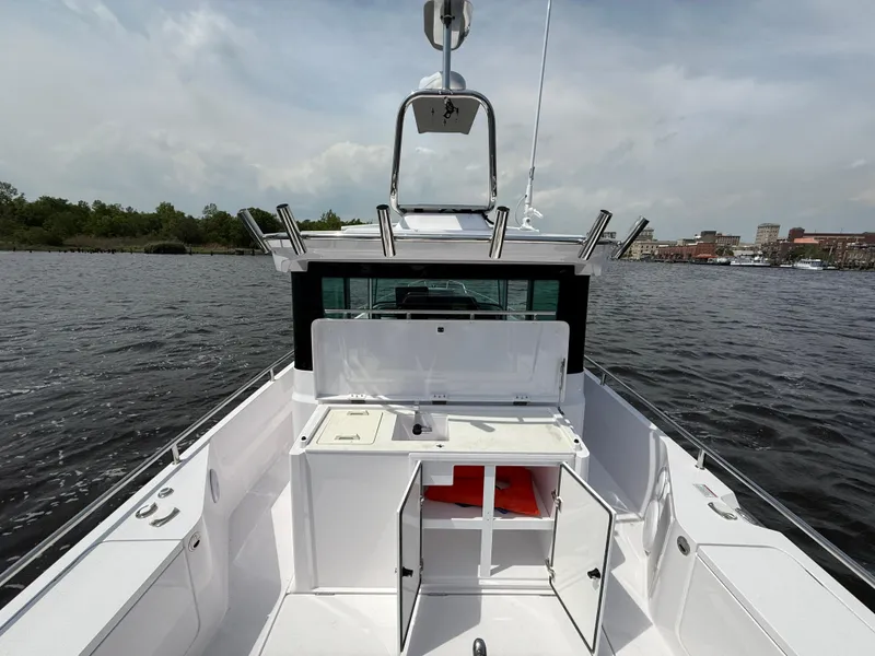 Slide: The Image of 2021 Axopar 28 CABIN boat on water, open storage compartments, clear sky background. - 9