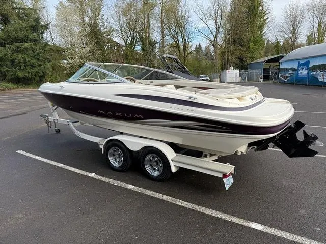Slide: The Image of 2000 Maxum 2100SR boat on trailer in parking lot, surrounded by trees. - 2