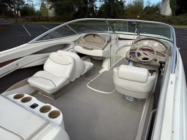 Slide: The Image of 2000 Maxum 2100SR boat interior with white seating and dashboard, parked outdoors. - 6