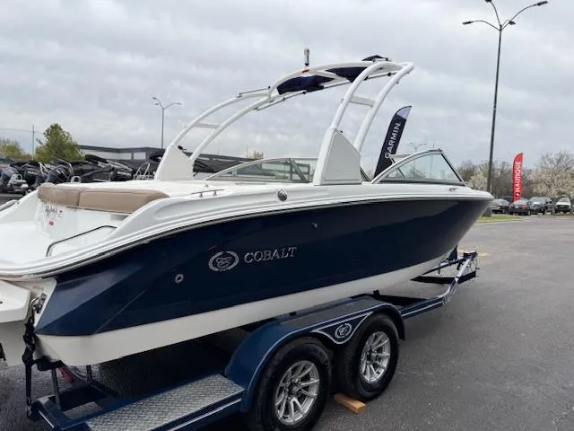 Slide: The Image of 2012 Cobalt 220S boat on trailer, blue and white design, parked outdoors. - 22