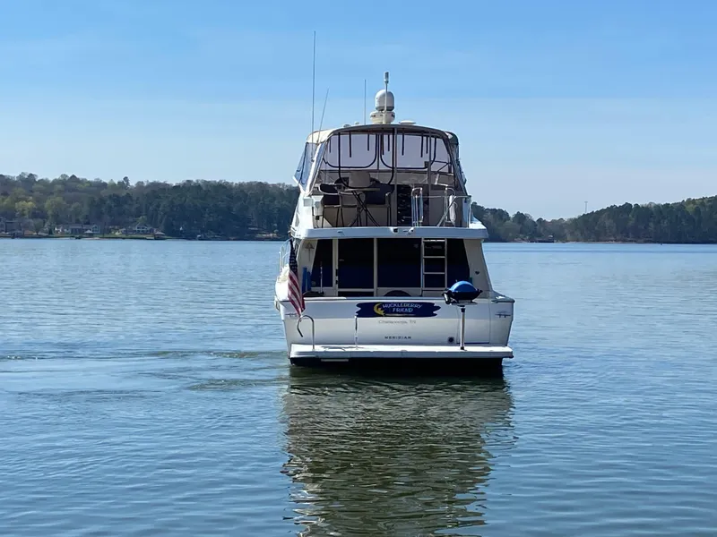Slide: The Image of 2008 Meridian 490 Pilothouse yacht on a serene lake with forested shoreline. - 3