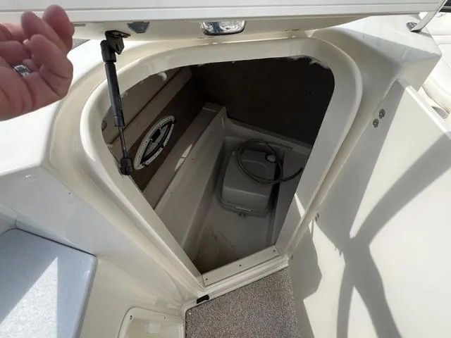 Slide: The Image of 2005 Stingray 220 DR boat storage compartment with portable toilet and speaker. - 11