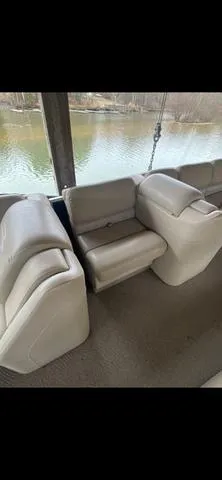 Slide: The Image of 2011 Bennington 2550 RCL boat interior with beige seating by the water. - 9