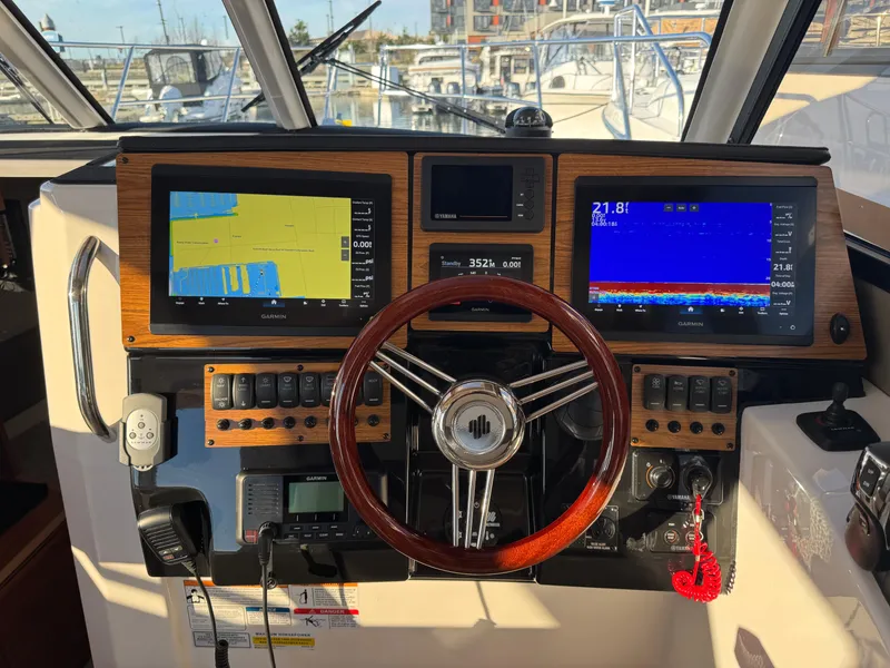 Slide: The Image of 2025 Cutwater C-288 Coupe dashboard with navigation screens and wooden steering wheel. - 19