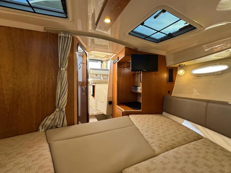 Slide: The Image of 2025 Cutwater C-288 Coupe interior cabin with bed, TV, and bathroom. - 32