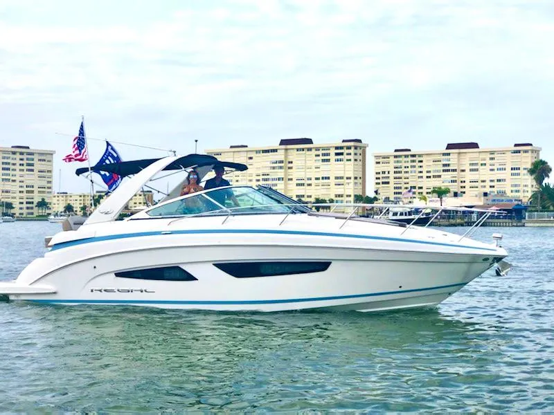 Slide: The Image of 2017 Regal 32 Express boat cruising near waterfront buildings. - 0