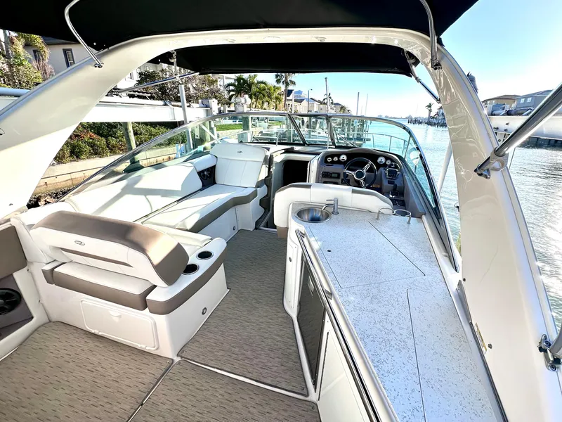 Slide: The Image of 2017 Regal 32 Express boat interior with seating, helm, and kitchenette, docked by a waterfront. - 17