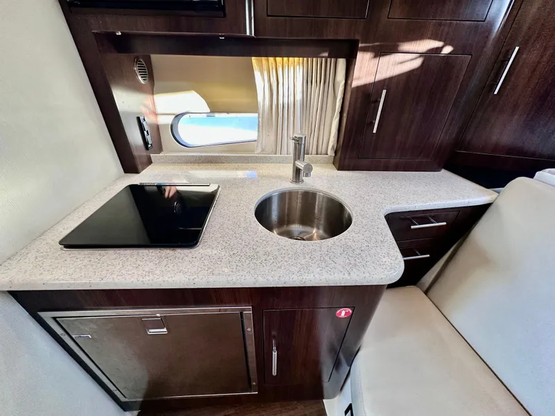 Slide: The Image of 2017 Regal 32 Express yacht kitchen with sink, stovetop, and dark wood cabinetry. - 40