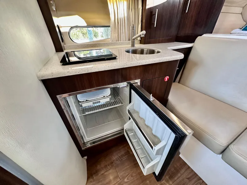 Slide: The Image of Compact kitchen area in a 2017 Regal 32 Express boat with open fridge and sink. - 41