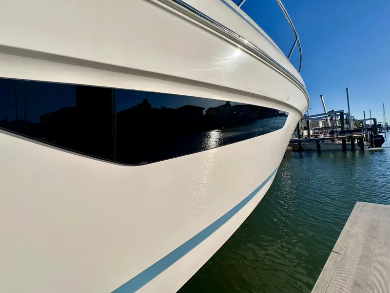 Slide: The Image of 2017 Regal 32 Express yacht docked, reflecting sunlight on calm water. - 9