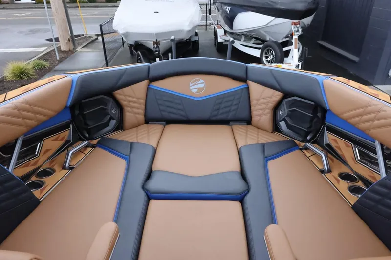 Slide: The Image of 2025 Tigé Ultré 25ZX boat interior with tan and blue seating, featuring cup holders and speakers. - 28