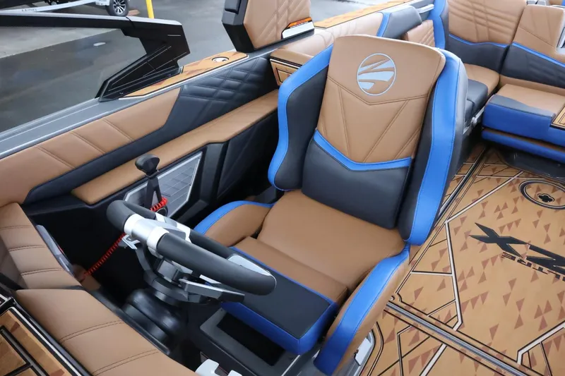 Slide: The Image of 2025 Tigé Ultré 25ZX boat interior with brown and blue seating, modern steering wheel. - 29