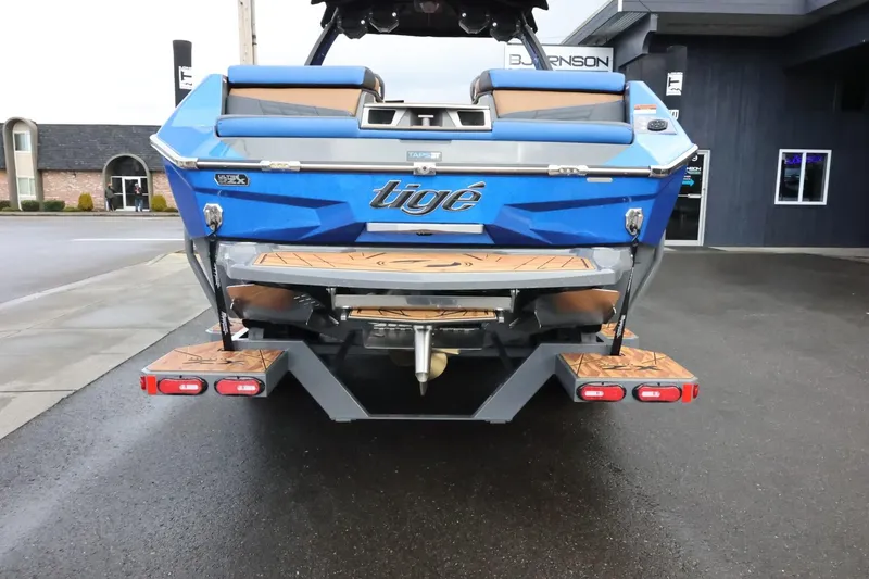 Slide: The Image of 2025 Tigé Ultré 25ZX boat, rear view, blue exterior, parked on wet pavement. - 3