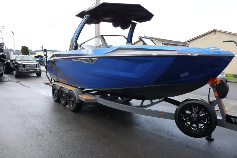 Slide: The Image of 2025 Tigé Ultré 25ZX boat in blue on a trailer, parked on a street. - 6