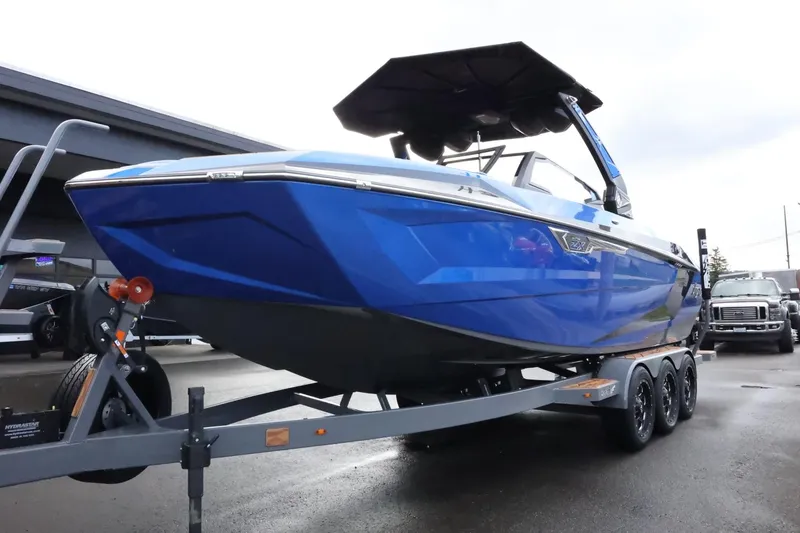Slide: The Image of 2025 Tigé Ultré 25ZX boat in blue on a trailer, parked outdoors. - 8