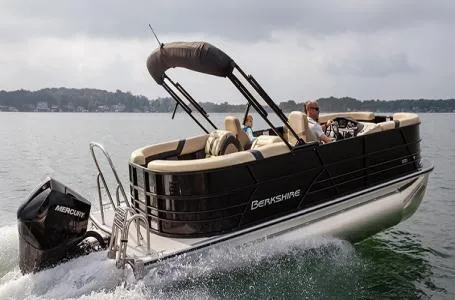 Slide: The Image of 2025 Berkshire CTS Series 24UL pontoon boat cruising on a lake with Mercury outboard motor. - 1