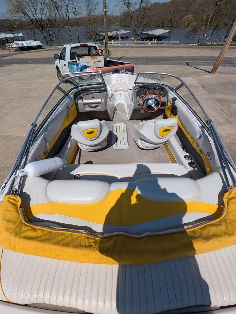 Slide: The Image of 2006 Crownline 180 BR boat interior with yellow and white seating, parked near a lake. - 6