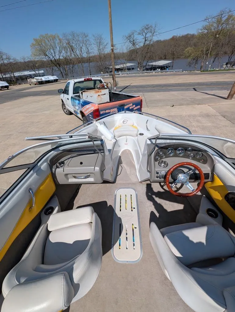 Slide: The Image of 2006 Crownline 180 BR boat interior with steering wheel, seats, and dashboard, parked near a lake. - 8