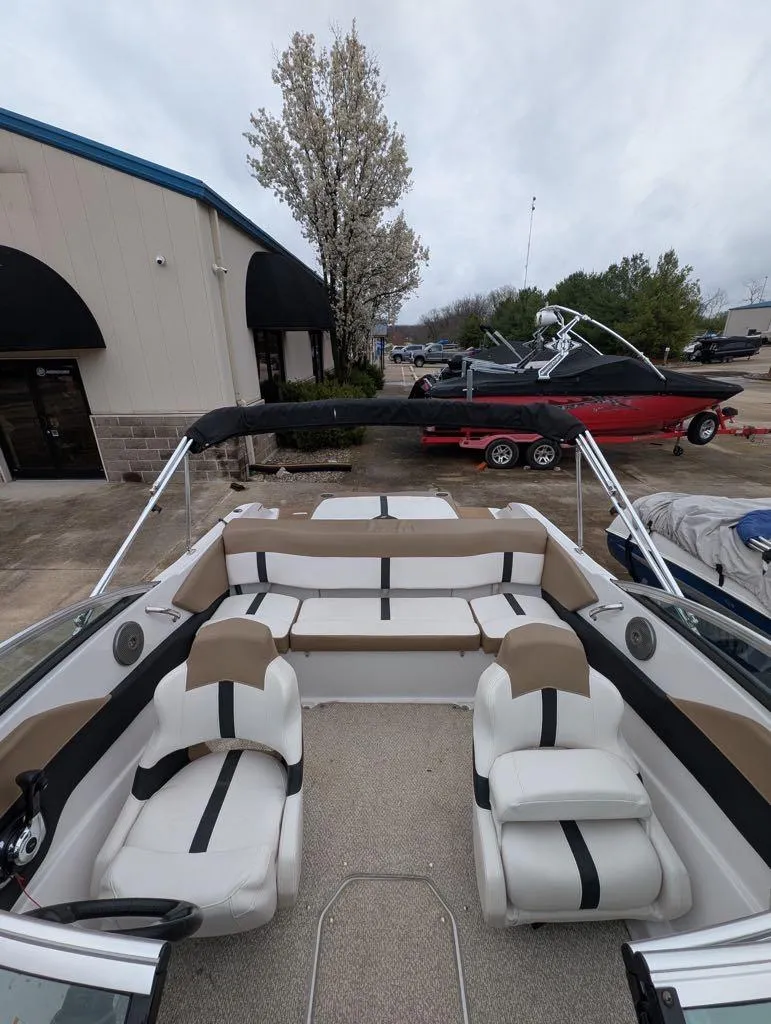 Slide: The Image of 2016 Four Winns 180 Horizon boat interior with seating, parked near a building. - 8