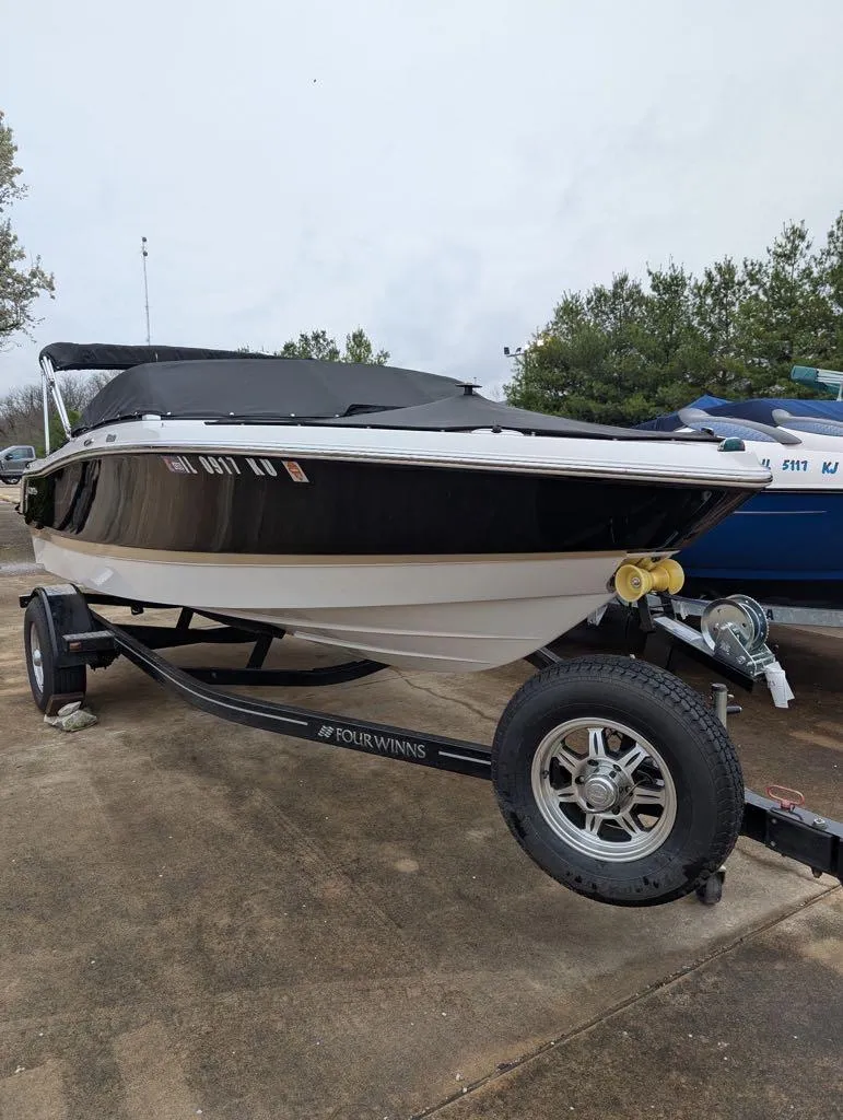 Slide: The Image of 2016 Four Winns 180 Horizon boat on trailer, black and white exterior, parked outdoors. - 9