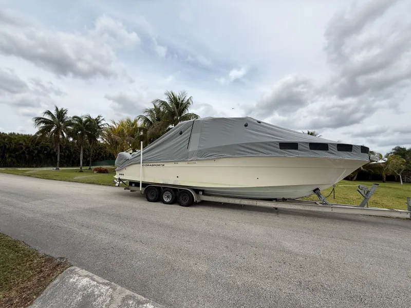 Slide: The Image of 2005 Hydra-Sports 3300 VX boat covered on trailer, parked near palm trees. - 33