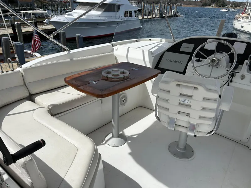 Slide: The Image of 2006 Beneteau 42 Swift Trawler cockpit with seating, table, and steering wheel, docked at marina. - 11