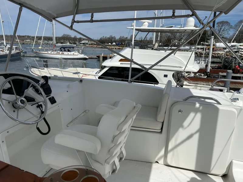 Slide: The Image of 2006 Beneteau 42 Swift Trawler helm with white seating, docked in a marina. - 14