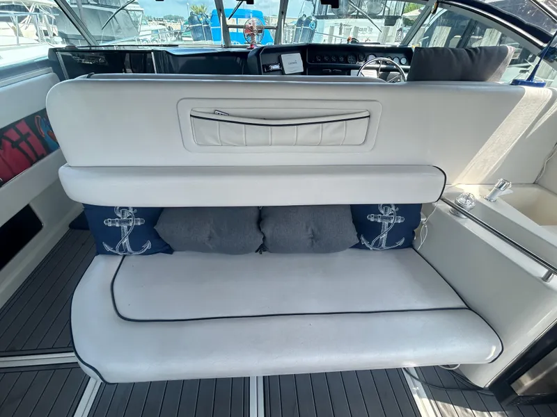 Slide: The Image of 1990 Sea Ray 350 Sundancer interior with cushioned seating and nautical-themed pillows. - 11