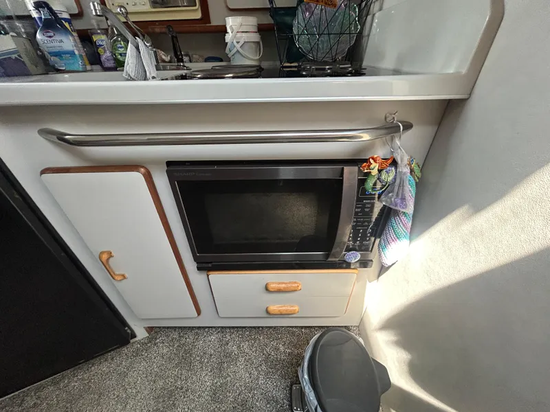 Slide: The Image of 1990 Sea Ray 350 Sundancer kitchen with microwave, cabinets, and countertop accessories. - 18