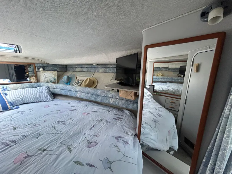 Slide: The Image of Cozy interior of 1990 Sea Ray 350 Sundancer with bed, mirror, and TV. - 23