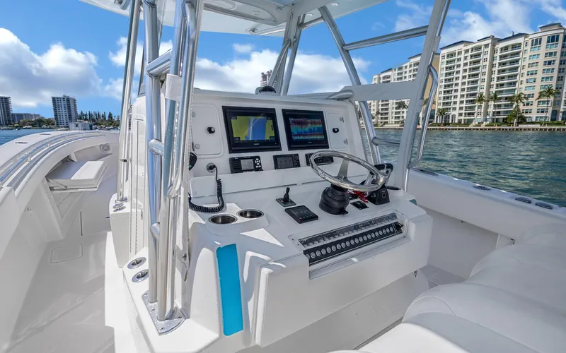 Slide: The Image of Helm of 2016 Invincible 39 boat with modern navigation equipment, docked near waterfront buildings. - 39