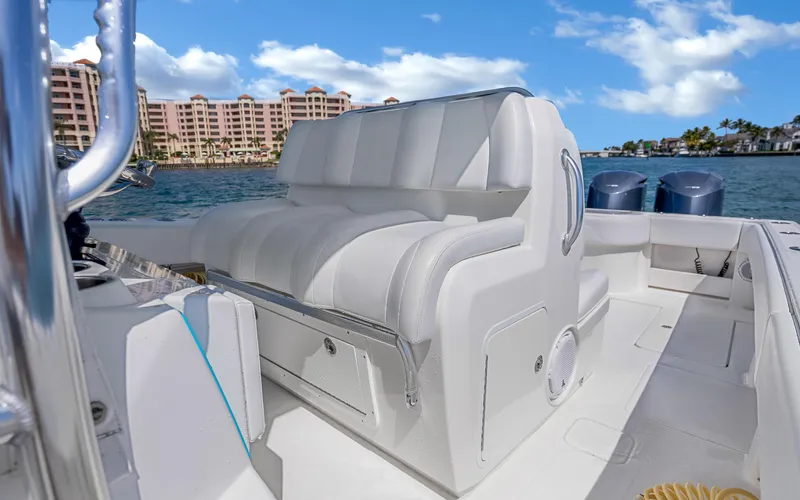 Slide: The Image of 2016 Invincible 39 boat interior with white seating, ocean view, and coastal buildings in the background. - 41
