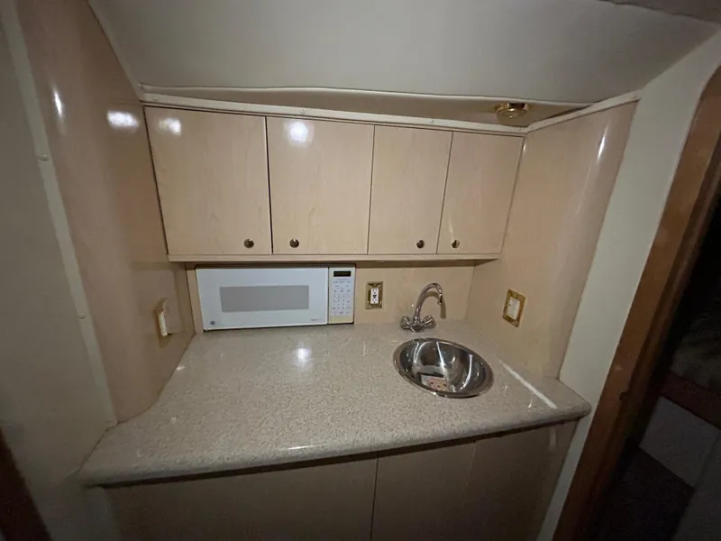 Slide: The Image of Compact kitchen area in a 2002 Fountain 38 Express Cruiser with cabinets, sink, and microwave. - 26