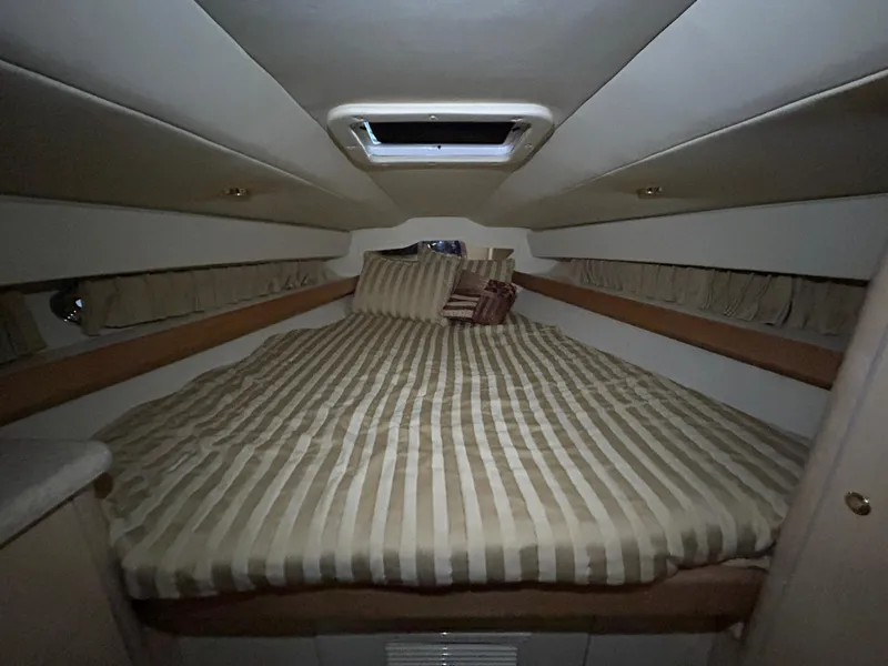 Slide: The Image of 2002 Fountain 38 Express Cruiser cabin with striped bedding and overhead hatch. - 27