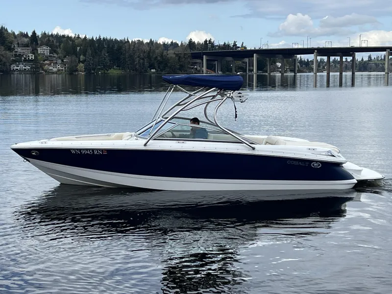 Slide: The Image of 2009 Cobalt 230 boat on a calm lake with a bridge in the background. - 1