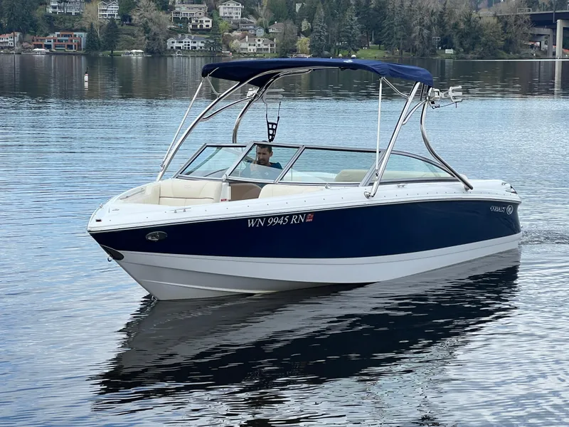 Slide: The Image of 2009 Cobalt 230 boat cruising on a serene lake with scenic background. - 10