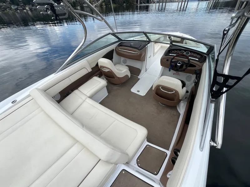Slide: The Image of 2009 Cobalt 230 boat interior with beige seating and sleek dashboard on calm water. - 13