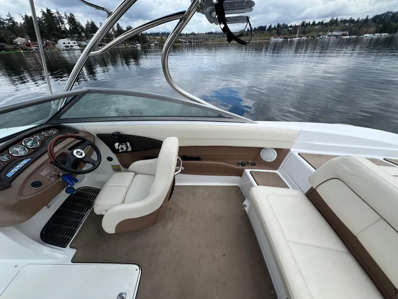 Slide: The Image of 2009 Cobalt 230 boat interior with steering wheel, beige seating, and lake view. - 17