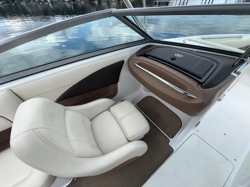 Slide: The Image of 2009 Cobalt 230 boat interior with white and brown seating, overlooking calm water. - 19