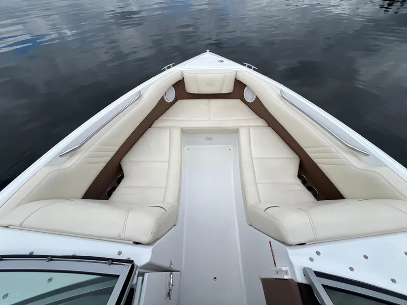 Slide: The Image of 2009 Cobalt 230 boat interior with white and brown seating on calm water. - 23