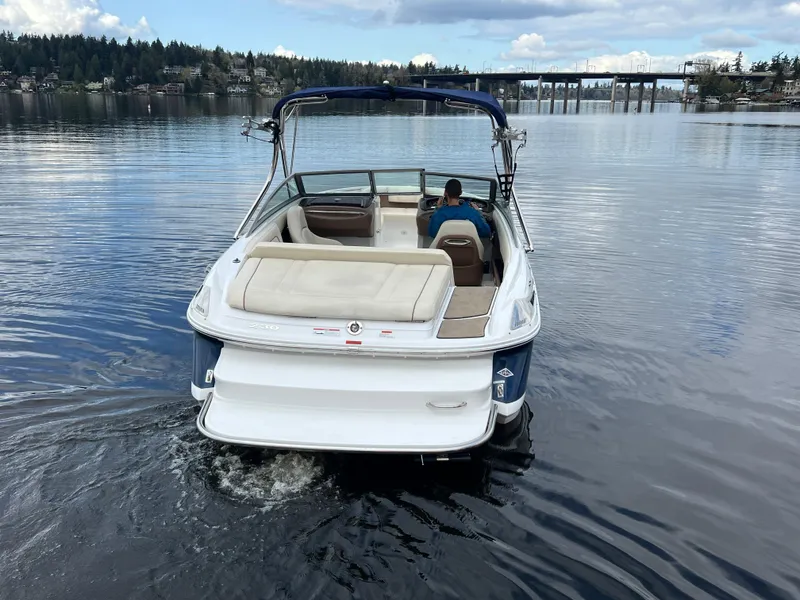 Slide: The Image of 2009 Cobalt 230 boat cruising on a calm lake with scenic background. - 4