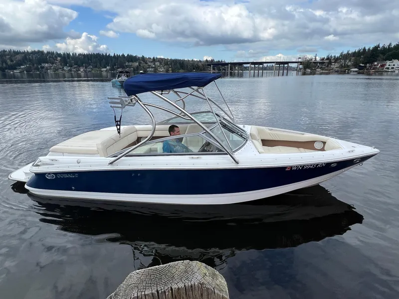 Slide: The Image of 2009 Cobalt 230 boat with blue hull and canopy on a calm lake. - 7