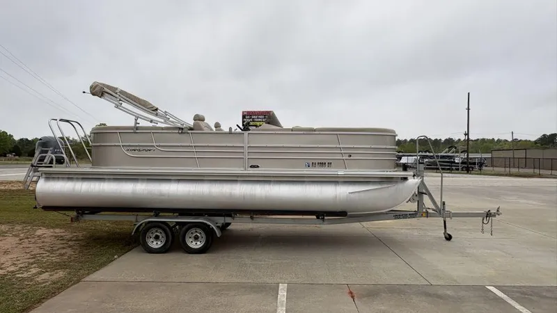 Slide: The Image of 2016 Starcraft EX23 R pontoon boat on trailer, parked outdoors. - 2
