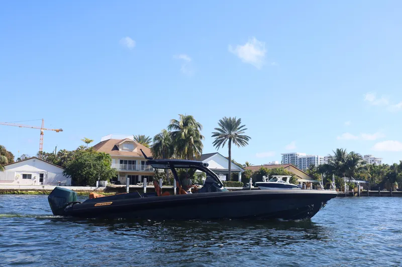 Slide: The Image of Skipper-BSK 38 boat cruising on a sunny day near waterfront homes, 2025 model. - 6