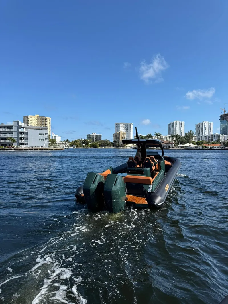 Slide: The Image of Skipper-BSK 38 boat cruising on water, city skyline in background, 2025 model. - 14