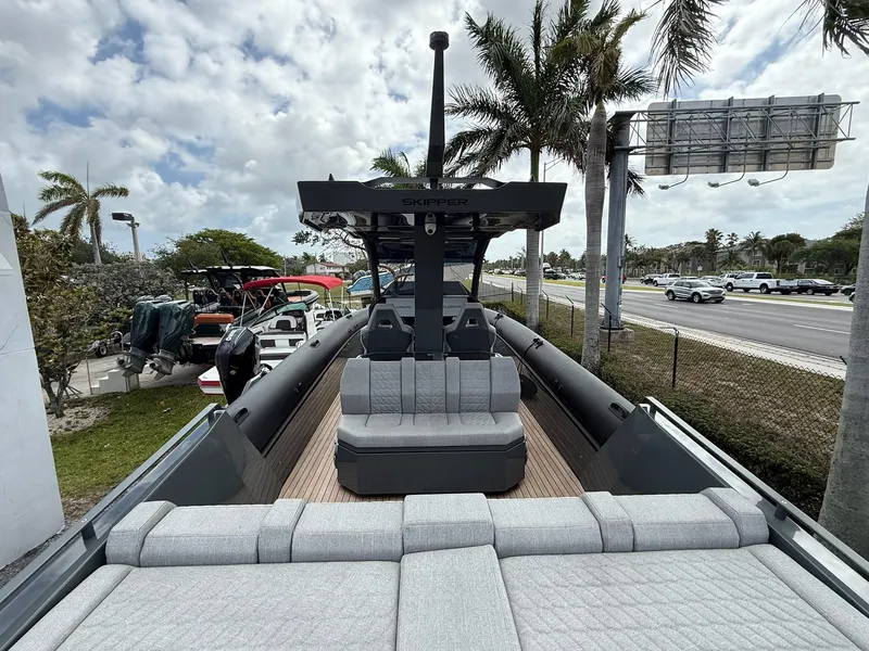 Slide: The Image of 2025 Skipper-BSK 38 boat with modern seating, docked near palm trees and a highway. - 26