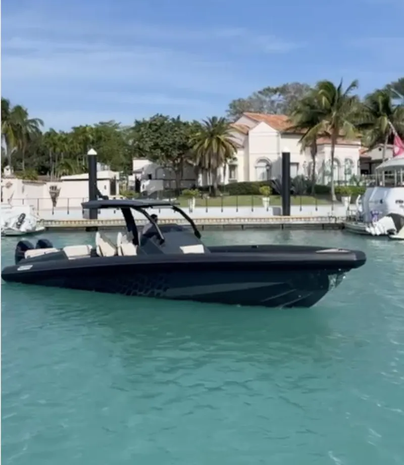 Slide: The Image of 2024 Skipper-BSK 38 boat in a tropical marina with palm trees and clear blue water. - 0