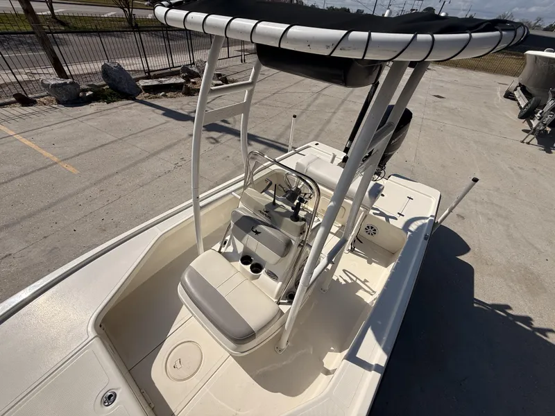 Slide: The Image of 2021 Mako 18 LTS boat with T-top, console, and seating, parked outdoors. - 11