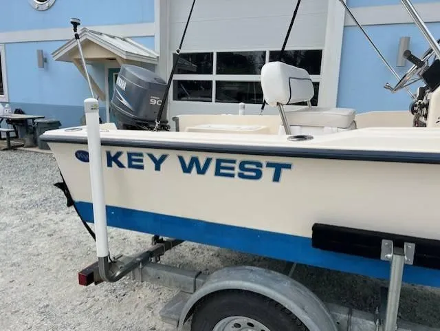Slide: The Image of 2003 Key West 1720 CC boat on trailer, parked outside a blue building. - 7