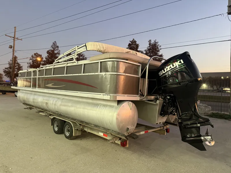 The Image of 2008 South Bay 25 pontoon boat with Suzuki outboard motor on trailer at dusk. - 0